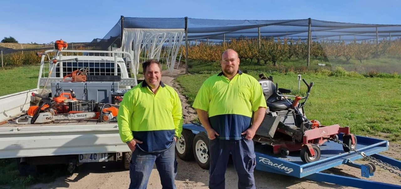 business owners Ken and Frank pictured in front of ute full of tools and trailer with mower